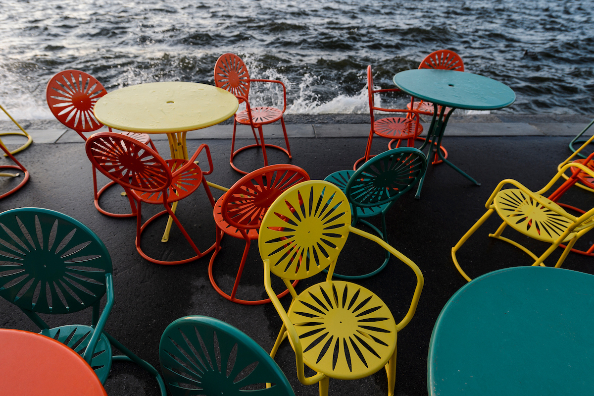 Yellow, orange, and blue terrace chairs arranged arund multiple tables