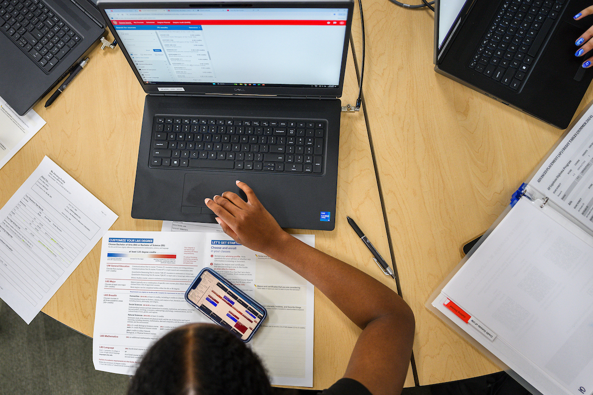 A person sitting at a table with a laptop and papers around them